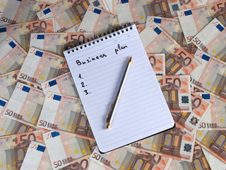 Notepad with business plan on euro currency background