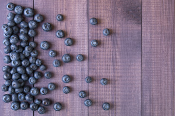 Ripe blueberry on a wooden table. Background of blue berries. Delicious and healthy food. Top view