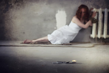 Young girl tied up on the floor. The abducted girl. The victim of violence sits on the floor with tied hands. Domestic violence.