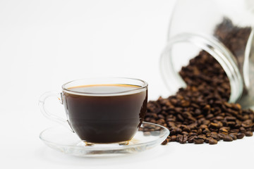 Black coffee in a glass cup and grains of coffee on a white background