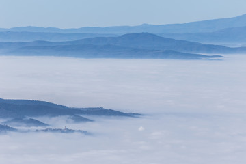 Fog filling a valley in Umbria (Italy), with layers of mountains and hills and various shades of blue