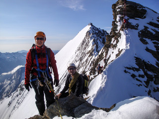 woman and man mountain climber on the way to a high mountain peak along a narrow rocky ridge