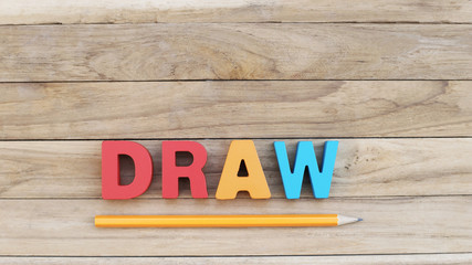 Colorful Word ' DRAW ' on Wooden Table with Orange Pencil Under Word