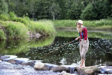 Girl by the river with a fishing rod