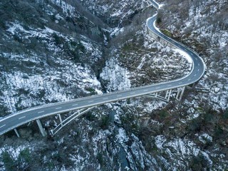Aerial view of road bridge in Switzerland over a deep valley in winter with snow covered ground....