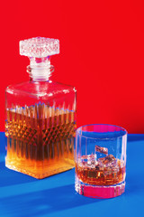 whiskey glass with decanter vertical on blue and red