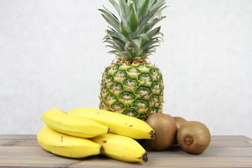 Banany, ananas i kiwi na jasnym tle - zdrowe jedzenie pełne witamin