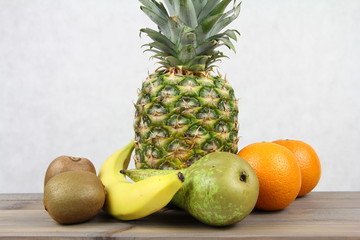Gruszka, pomarańcze, ananas, kiwi i banan na jasnym tle - energetyczne owoce