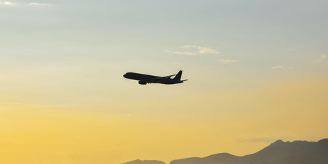 Fototapeta na wymiar silhouette of an airplane flying over the mountains against a clear sky . Copy space fot text