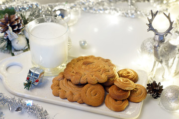 Gingerbread cookie and milk for Santa on a tray on a decorated table for Christmas with a deer, a garland and tinsel