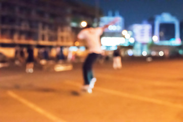 Skateboarder is jumping down street at night. image out of focus