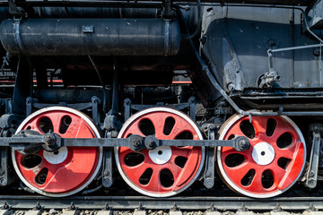Fototapeta na wymiar Wheels of the old locomotive of red color and the elements of the drive