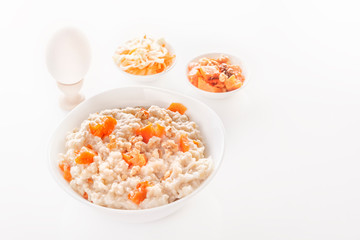 Fototapeta na wymiar Oatmeal with pumpkin and nuts in a plate, vegetable salads and boiled egg on a white background. Close-up. Copy space
