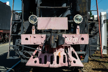 Old steam locomotive beside a railway station platform. Retro train.