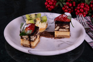 Tiny cupcake with kiwi, whipped cream and chocolate cake on a black marble table
