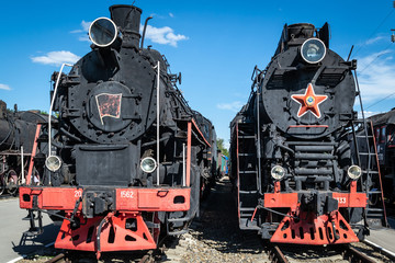 Old steam locomotive beside a railway station platform. Retro train.