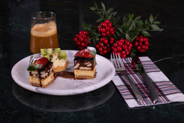 Tiny cupcake with kiwi, whipped cream and chocolate cake with coffee on a black marble table