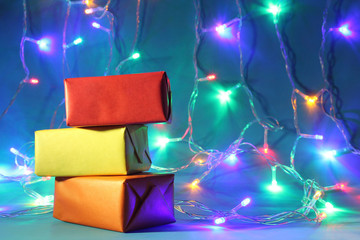 Festive colored gifts against the background of colored lights of a garland