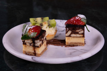 Tiny cupcake with kiwi, whipped cream and chocolate cake on a black marble table