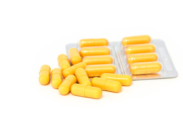 Bright yellow pills and blisters scattered on a white background. Isolated.