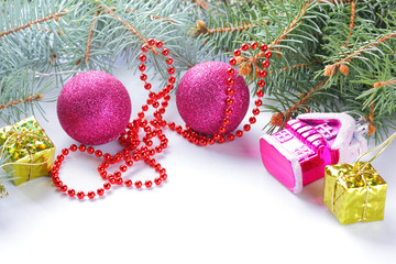 Christmas decorations. Christmas tree branches and pink balls on white background. Toy house and Christmas gifts. Red necklace for Christmas decorations on spruce
