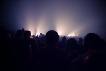 Fototapeta premium audience silhouettes crowd in large concert hall watching rock show.
