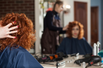 The woman in the hairdresser makes a new hairstyle. Reflection in the mirror blurred