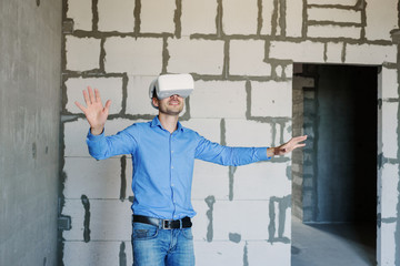 Builder projecting with VR glasses future interior standing at the construction site