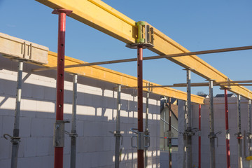 Stahlrohstützen und gelbe Holzträger für Betonfertigteile der Obergeschossdecke