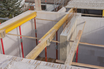 Stahlrohstützen und gelbe Holzträger für Betonfertigteile der Obergeschossdecke