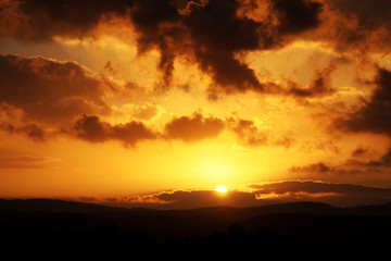 Fototapeta na wymiar Cloudy sunset above desert mountains