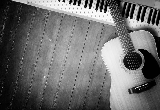 Musical instrument - MIDI keyboard and acoustic guitar wood background monochrome