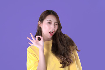 Fototapeta premium Asian woman accept deal with hand symbol, yellow t-shirt clothing, purple background