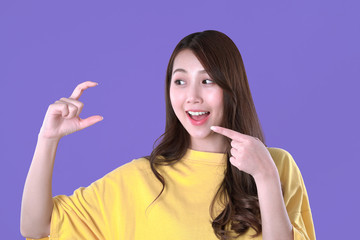 Asian woman recommended vitamin c with hand symbol, yellow t-shirt clothing, purple background