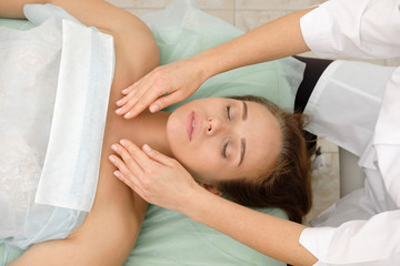 Young woman getting spa massage treatment at beauty spa salon. Cosmetologist making girl relaxing Face and head massage. Spa skin and body care. Facial beauty treatment.Cosmetology.
