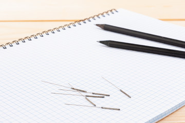 Naklejka premium Silver needles for traditional Chinese medicine acupuncture lie on a note book, on a wooden table.
