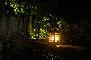 Retro style lantern at night. Beautiful colorful illuminated lamp at the balcony in the garden. Selective focus
