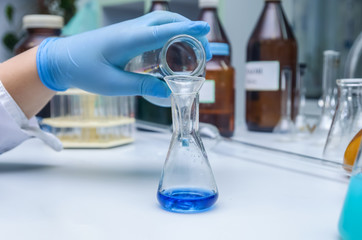 a chemist holds a glass test tube in his hand, overflows a liquid solution, conducts an analysis reaction using various reagent options using chemical production.