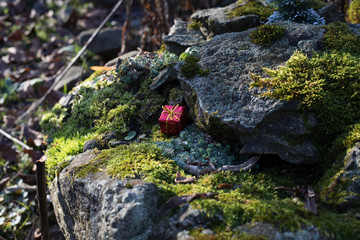 Christmas and New Year miniature house at forest in the sunlight. Little toy house close up. Festive background. Christmas decorations. Holiday and celebration concept.