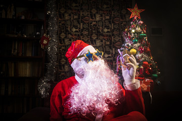 Santa Clause vaping electronic cigarette dressed as traditional Santa on a dark toned background...