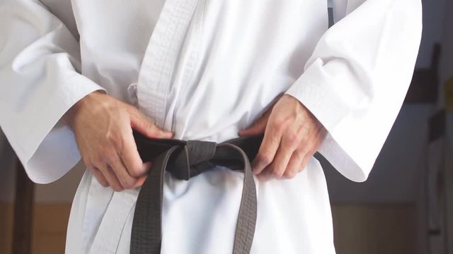 karate man Hands tightening black belt on man dressed in kimono