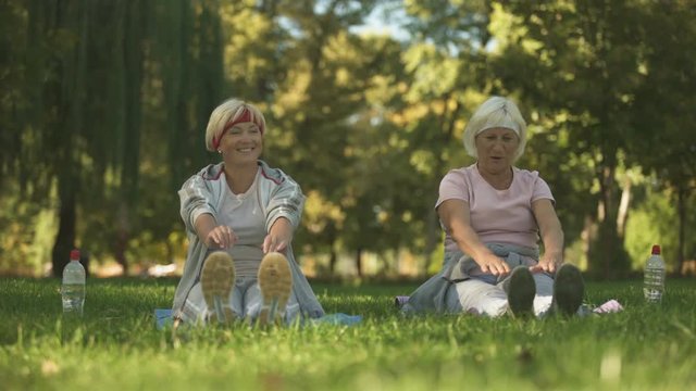 Middle and elder age women doing exercise in park, stretching their bodies