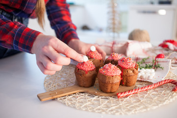 Girl decorates New Year celebration cupcakes, chocolate muffins on table
