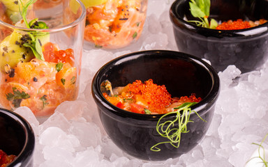 Caviar salmon with greens in a flat dish on ice