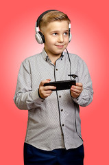 The boy listens to music with headphones with the phone in hands