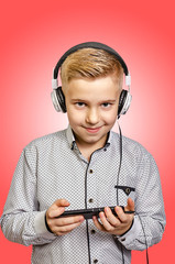The boy listens to music with headphones with the phone in hands