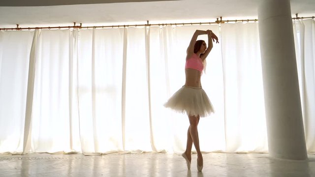Slender ballerina in pointe on tiptoe. Girl in tutu rehearsing. Ballet dancer. Graceful movements of legs and arms. Classic ballet.