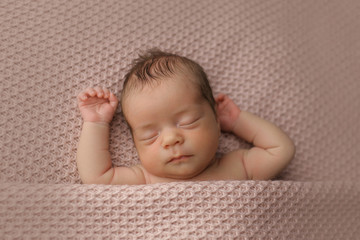 Breast baby sleeping on a textured blanket, spreading arms, close-up
