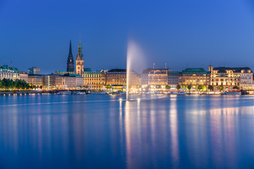 Fototapeta na wymiar The Inner Alster Lake (German: Binnenalster) in Hamburg, Germany. Evening view of the inner city at dusk with the fountain reflecting in the water.
