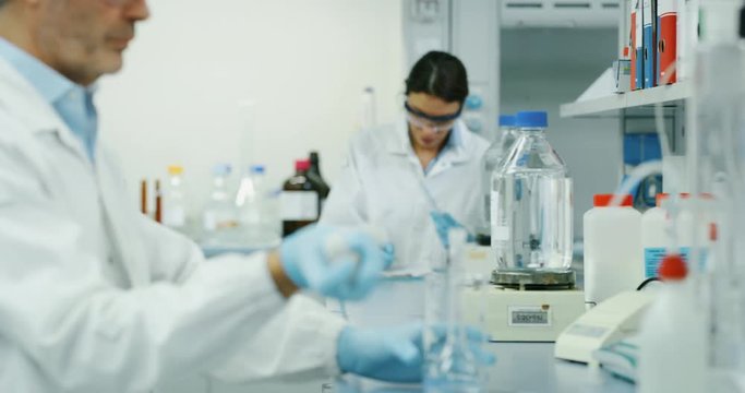 Portrait of male scientist with a pipette analyzes a liquid to extract the DNA and molecules in the test tubes in laboratory. Shot in 8K. Concept: research,biochemistry, pharmaceutical medicine